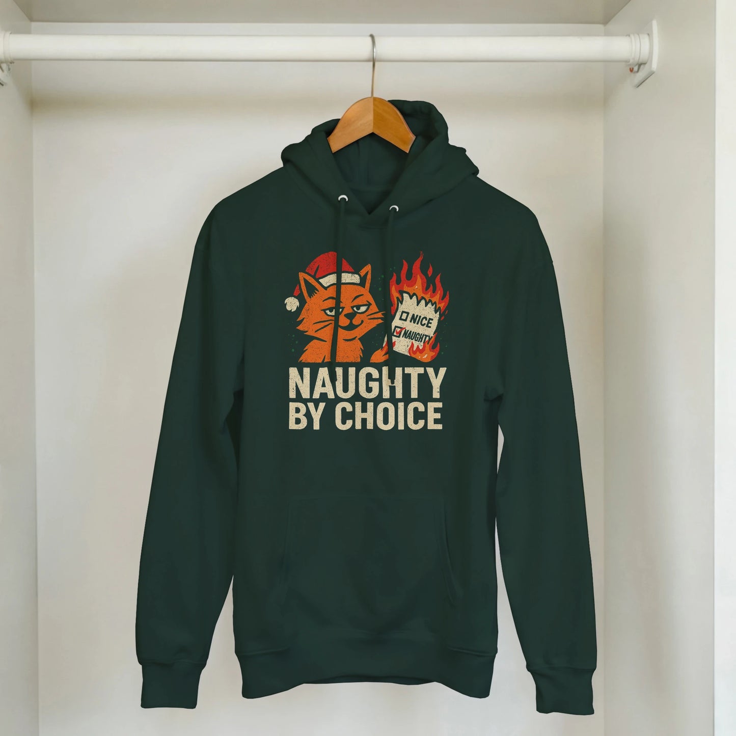Green Naughty By Choice hoodie hanging on a rack. Orange cat graphic with sarcastic holiday attitude.