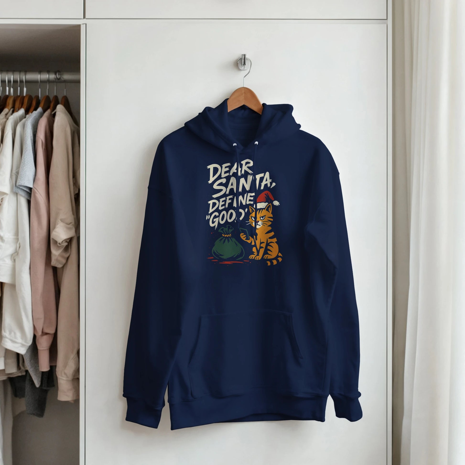 "Dear Santa, Define Good" hoodie hanging on hanger. Minimal LazyWhiskers holiday display.