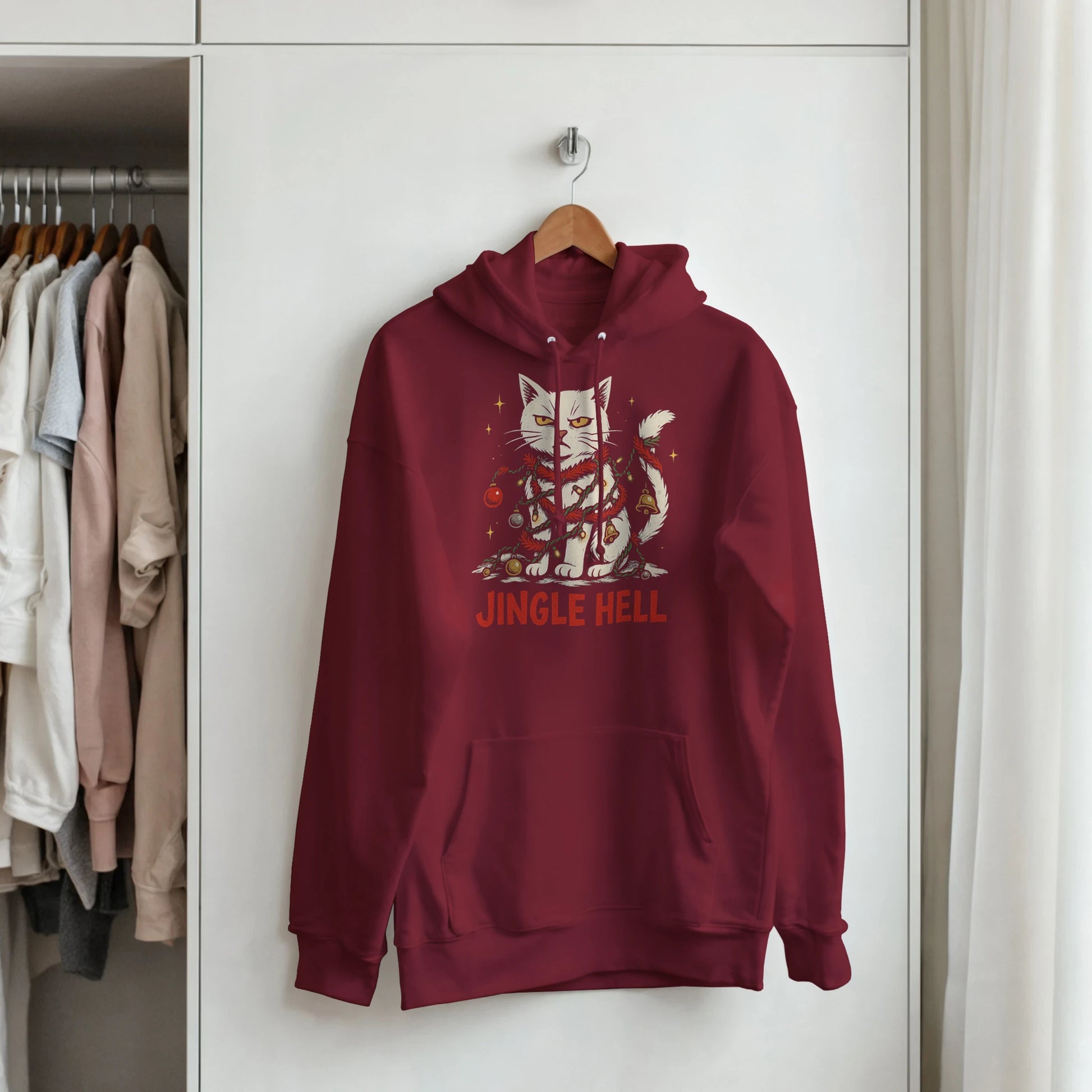 Red Jingle Hell hoodie hanging on a rack. Christmas cat graphic with sarcastic festive energy.